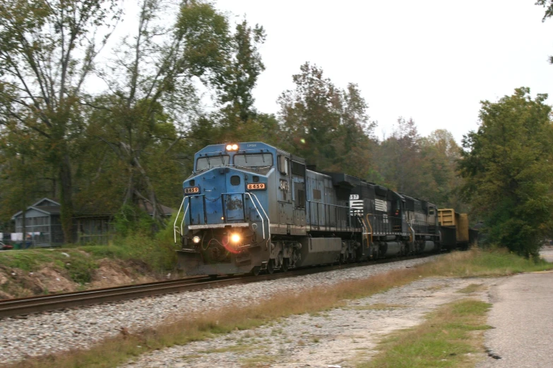 a long train on a steel track near a wooded area