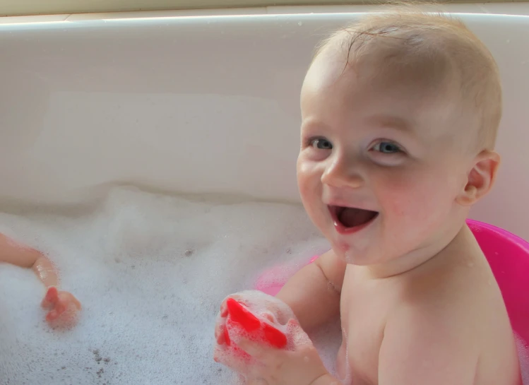 a little baby sitting inside of a bath tub