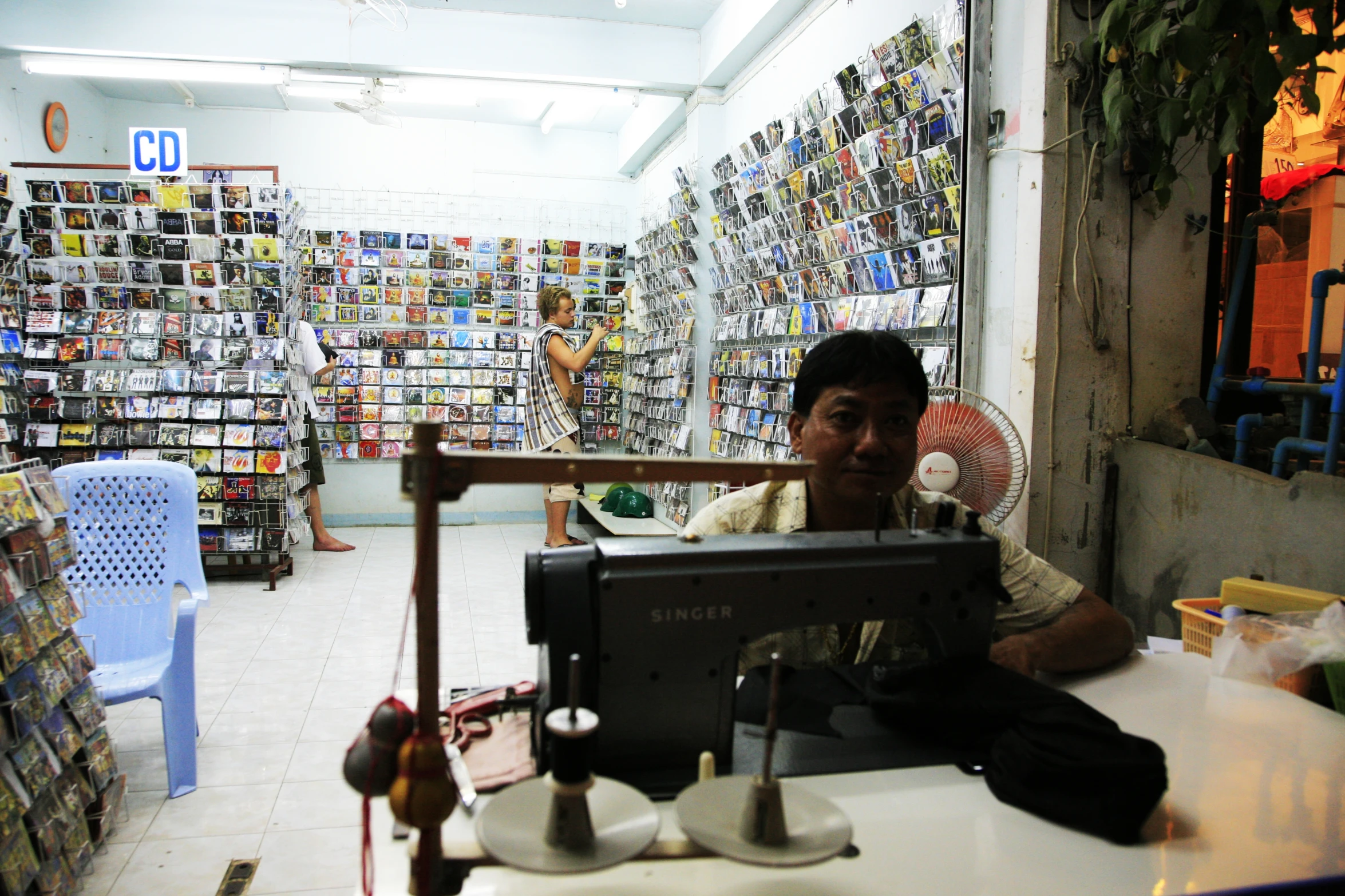 a man sitting behind a computer in a room with multiple pictures on the walls