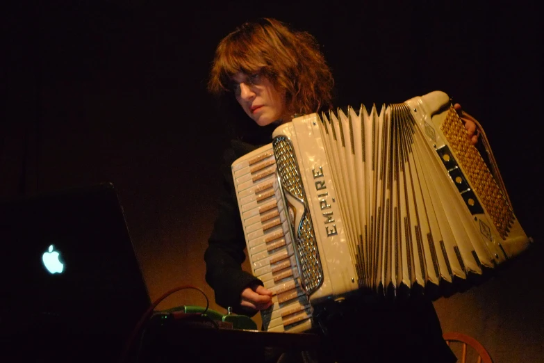 a man holding a on accordion in front of his computer