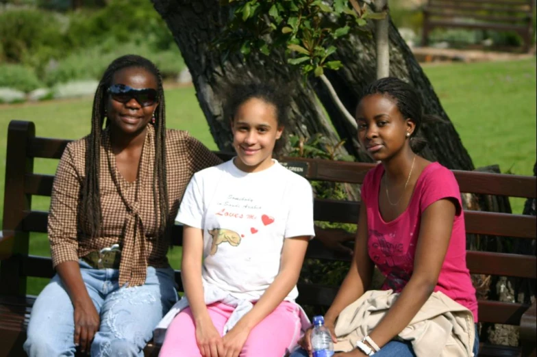 three women sitting on a bench with one smiling