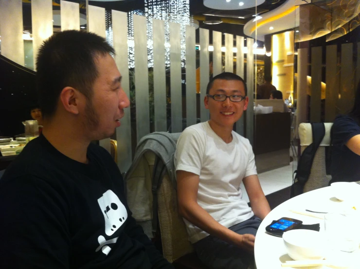 two men smile at each other while one person eats food