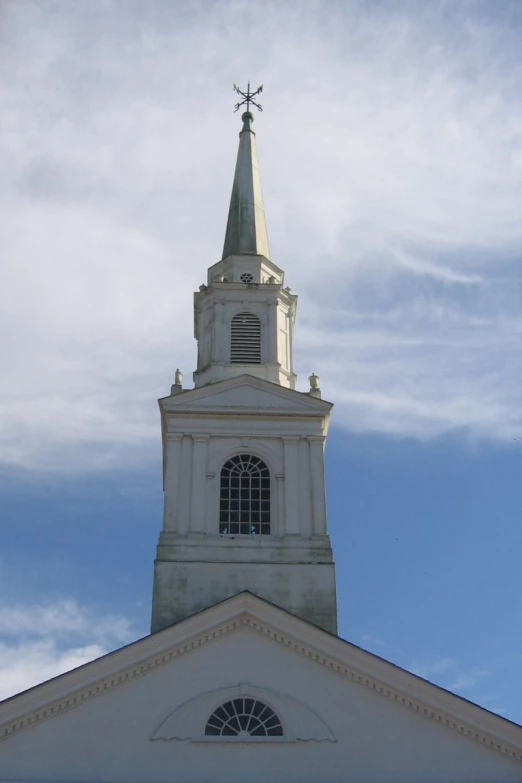 looking up at the spire of an old building with the weather vane on