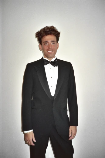 a man in a tuxedo poses for the camera