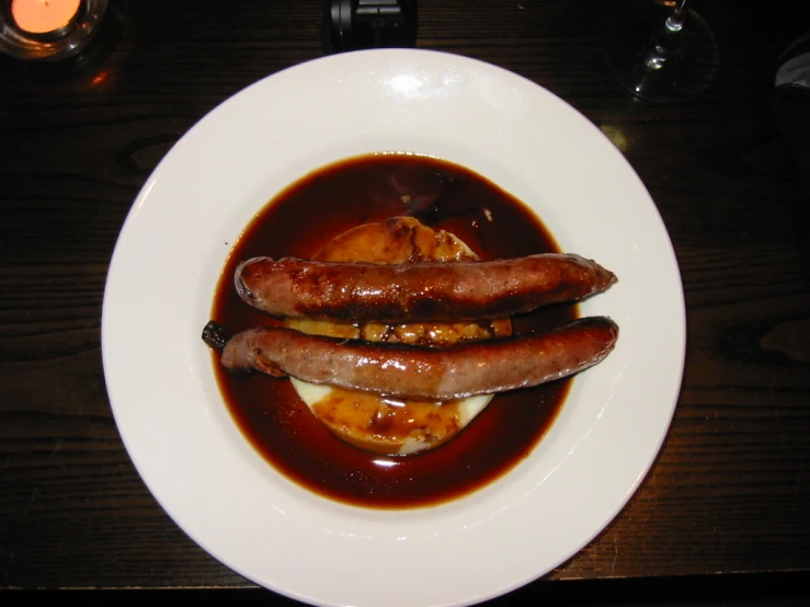 three cooked sausages and egg are served in an orange sauce