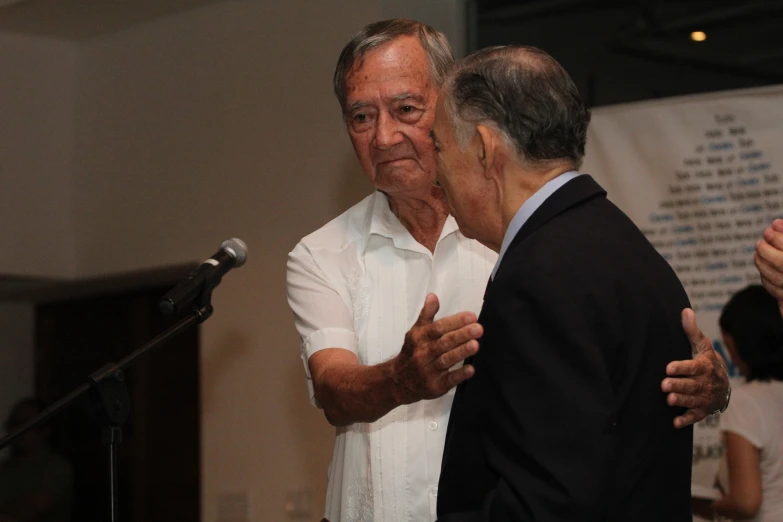 two men stand and talk while they speak to each other