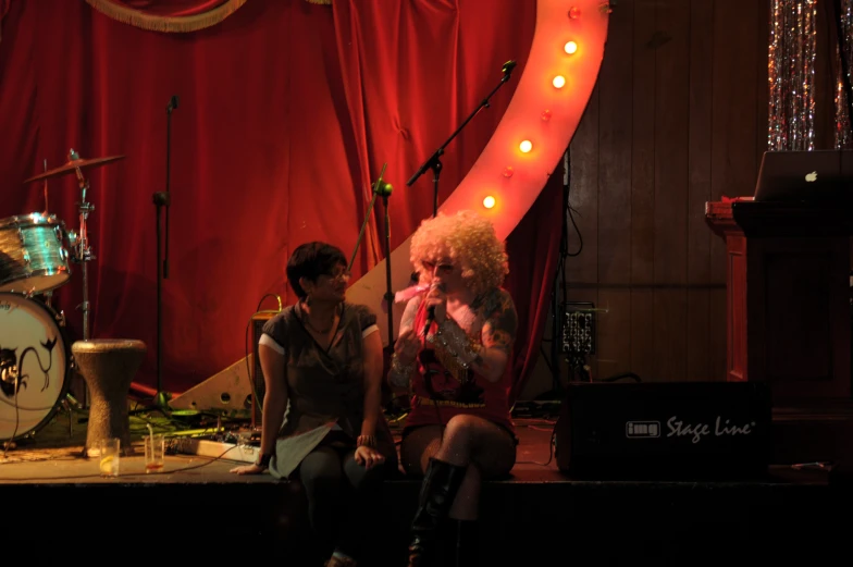 two people sitting on the stage while listening to music