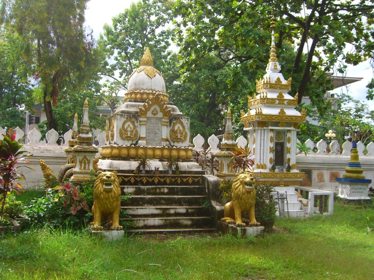 a statue of lions on the steps leading up to a gold and white temple