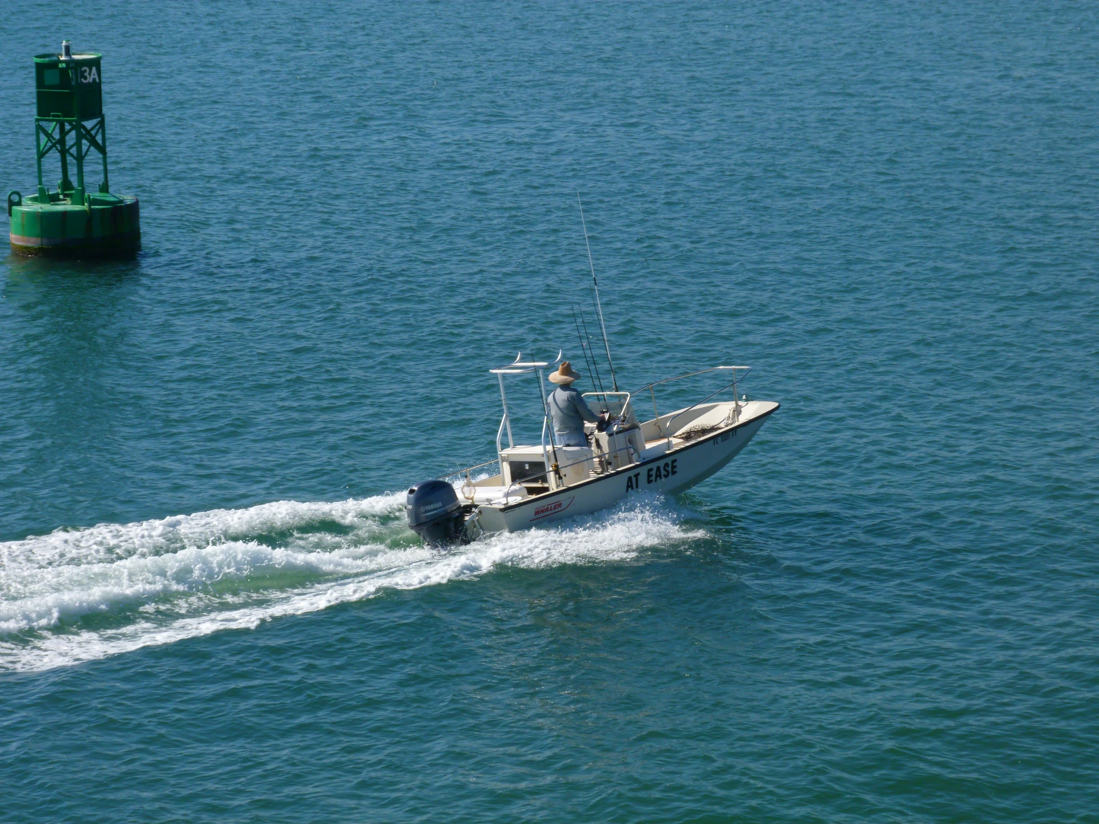 a boat in the ocean on the water near a green buoy