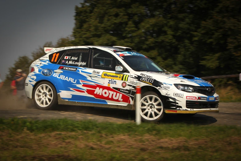 the subarun rally car is driving on a dirt track