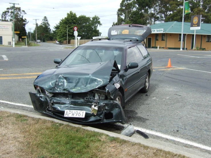 a damaged car sits on its side with a license plate in the middle of it