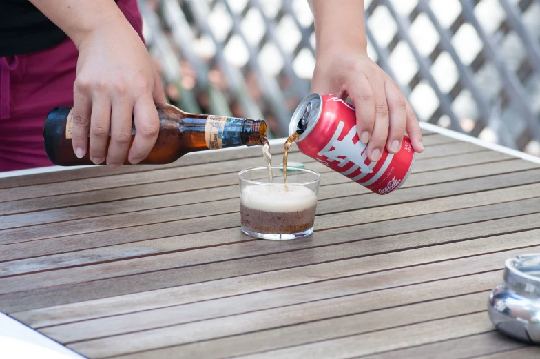 person pouring beer from a can into a cup