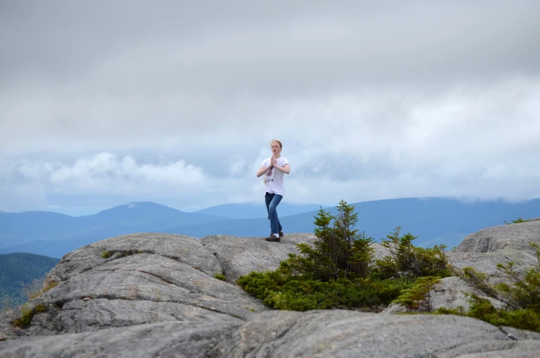 a girl standing on top of a large rock