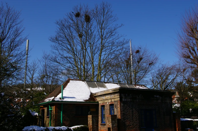 an old brick building is standing next to trees and a clear blue sky