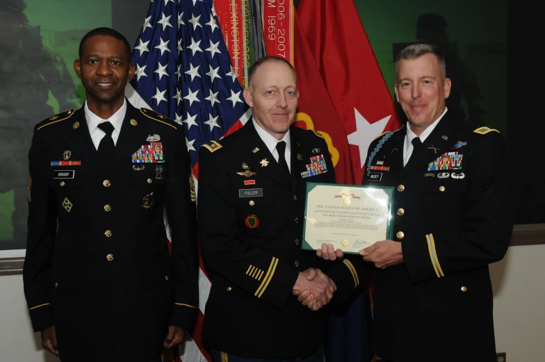 two soldiers in uniform shaking hands in front of flags