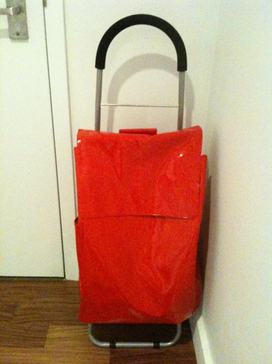 a red hand luggage cart sitting against the wall