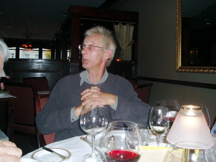 a man in grey shirt sitting at table with wine glasses