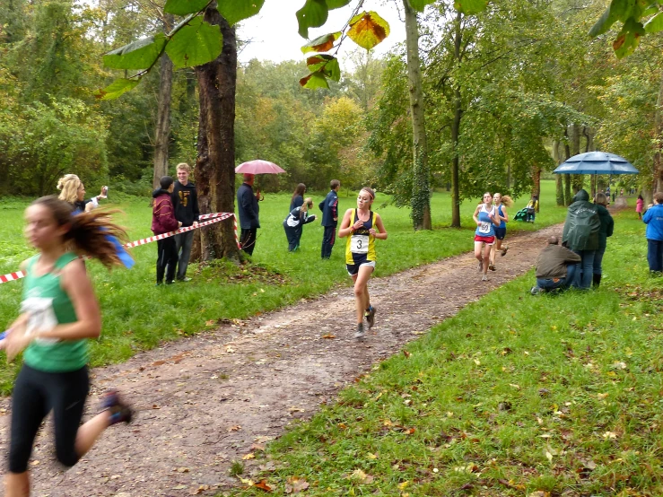 a woman running along a trail with a lot of people watching