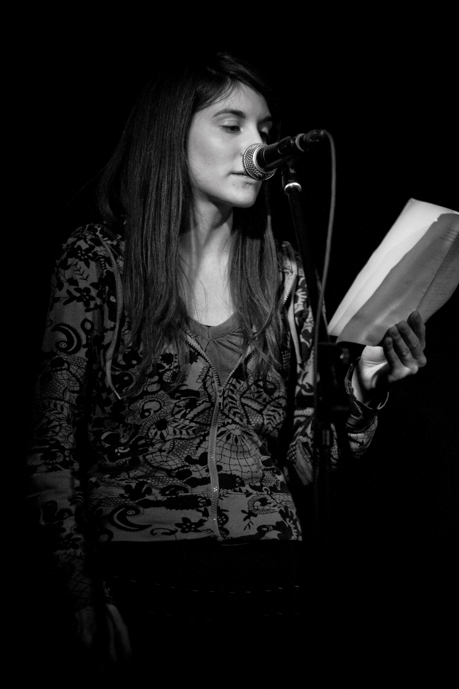 a woman holding a book at the microphone