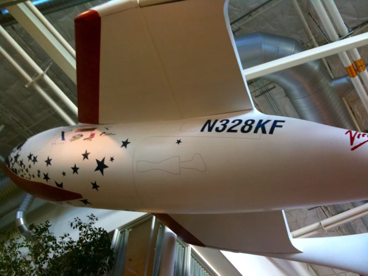 a white jet airplane is displayed in an open hangar