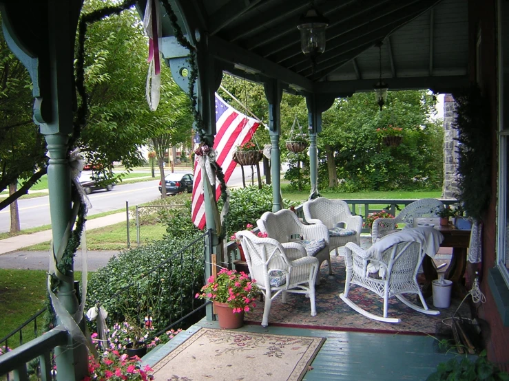 a porch area with several chairs and an american flag