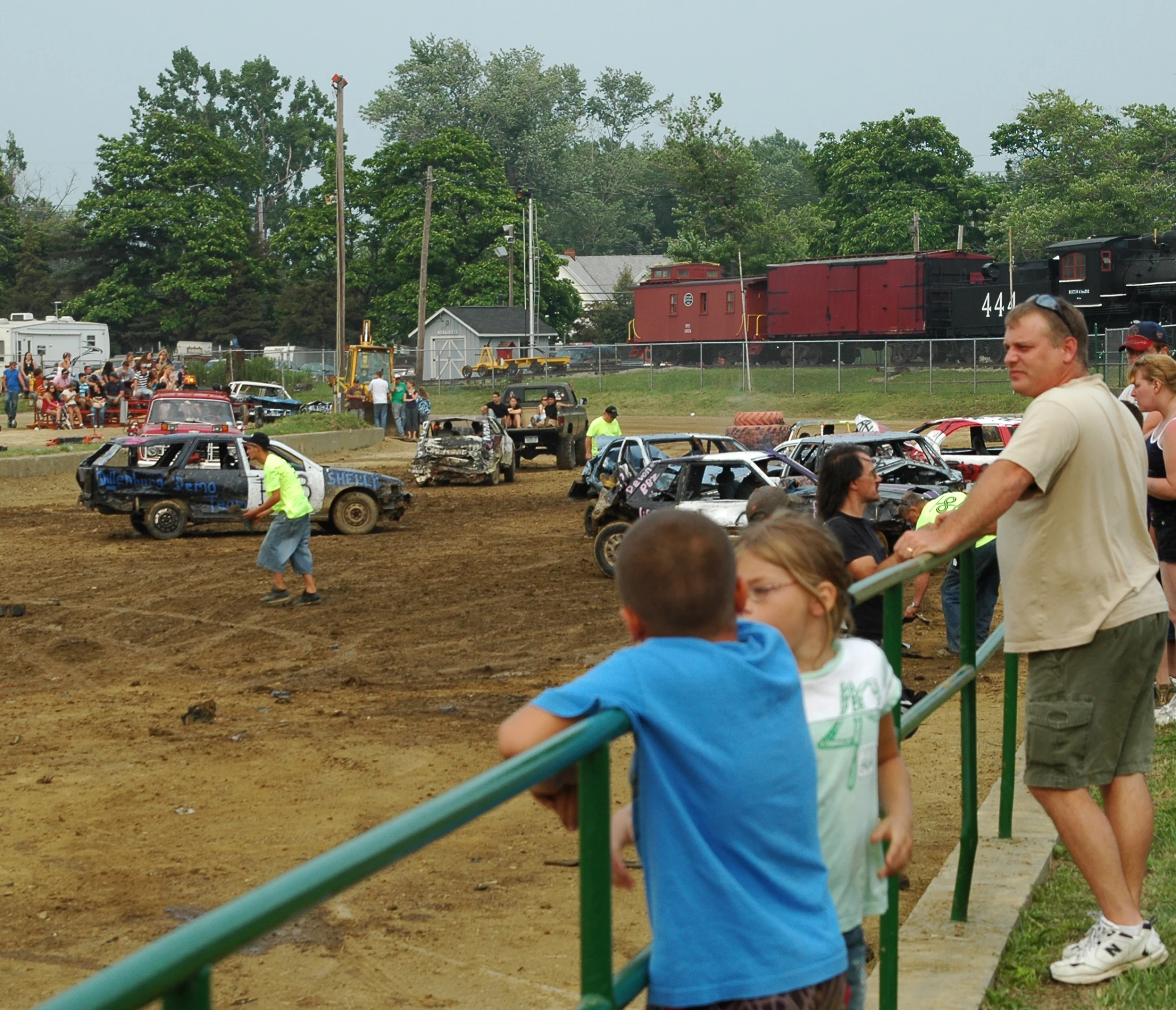 a group of young children watch people ride off cars