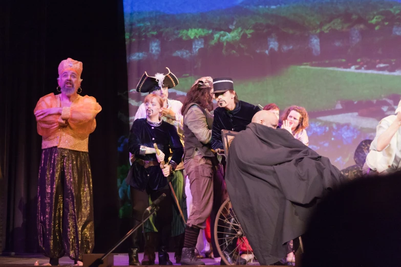 an audience looks on as an old time gentleman plays the fiddle