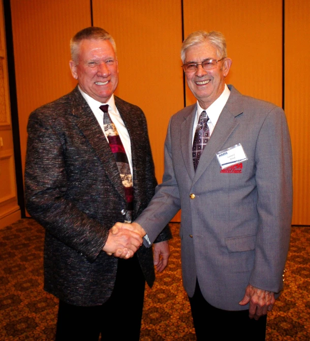 two men are shaking hands and smiling for the camera