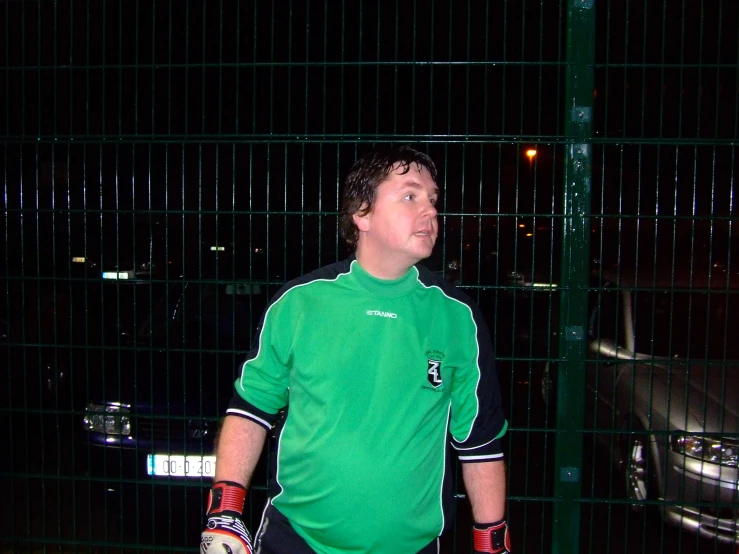 a man wearing green is holding his mitt and has his left hand behind him