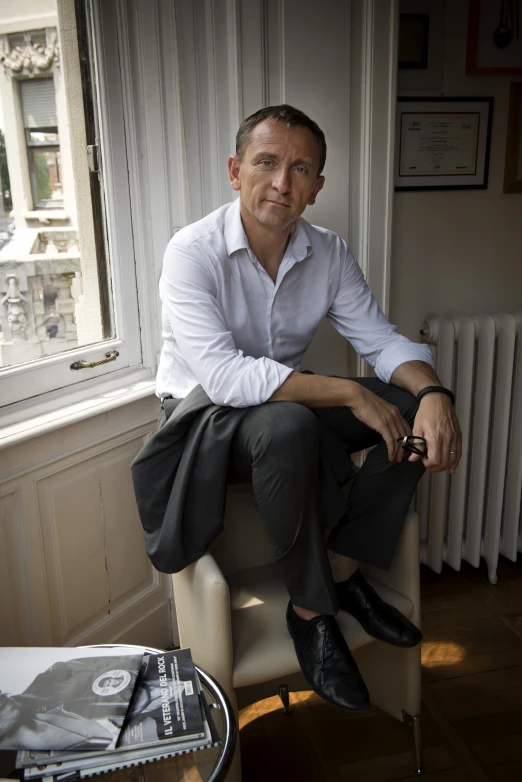 a man sitting in a chair wearing black shoes