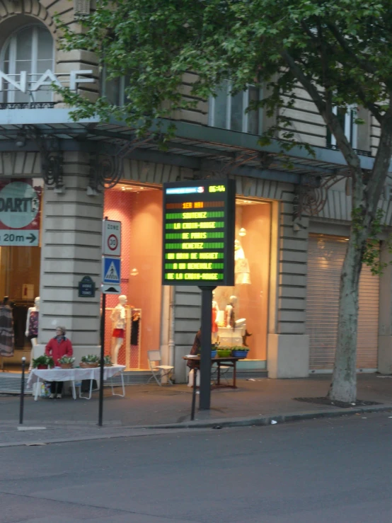 an outdoor store front with a sign showing the time and hours