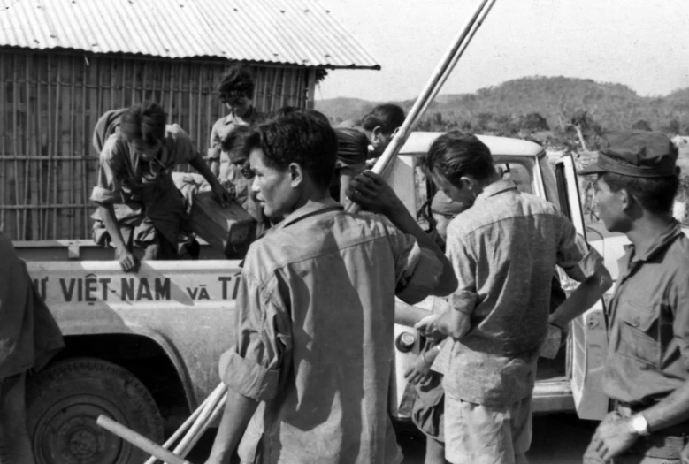 a group of people are standing near the back of a truck