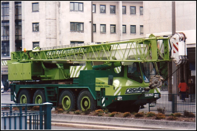 a green truck is being moved by a crane