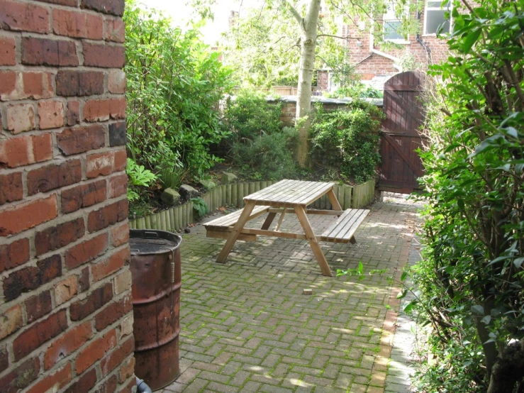 a picnic table sits next to a brick wall