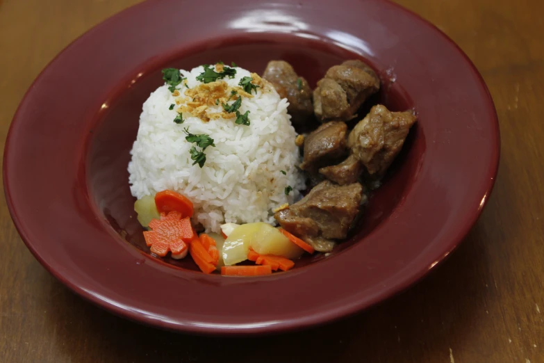 a red bowl with meat, rice and vegetables on it