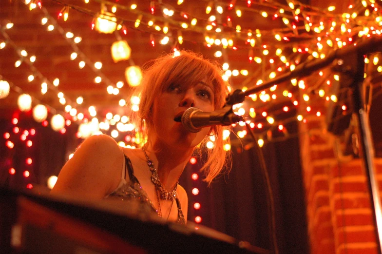 a woman singing into a microphone while standing on a stage