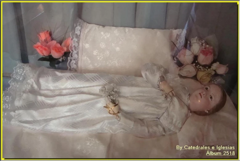 a baby laying on a white bed with a dress on