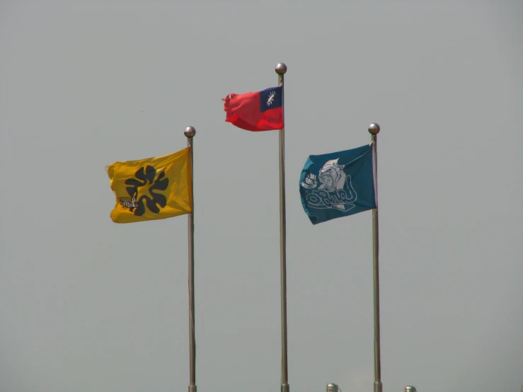 three different colors waving in the wind on flags