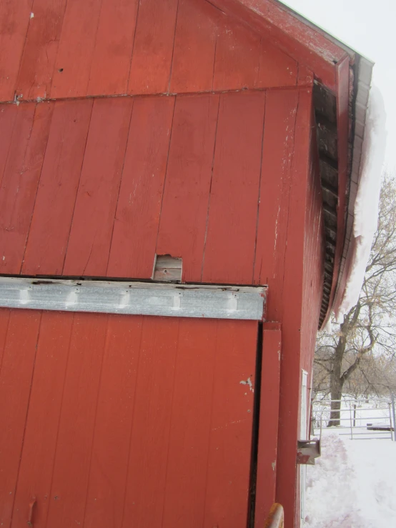 an old red barn covered in snow and ice