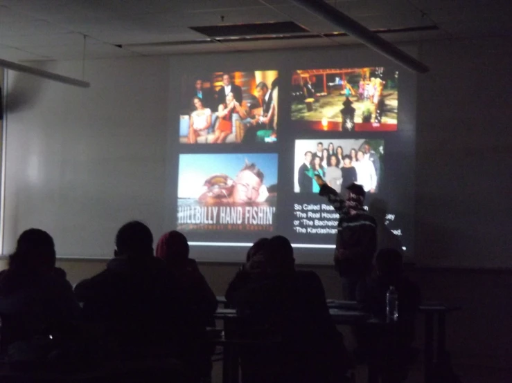 people sitting in chairs in front of a projector screen