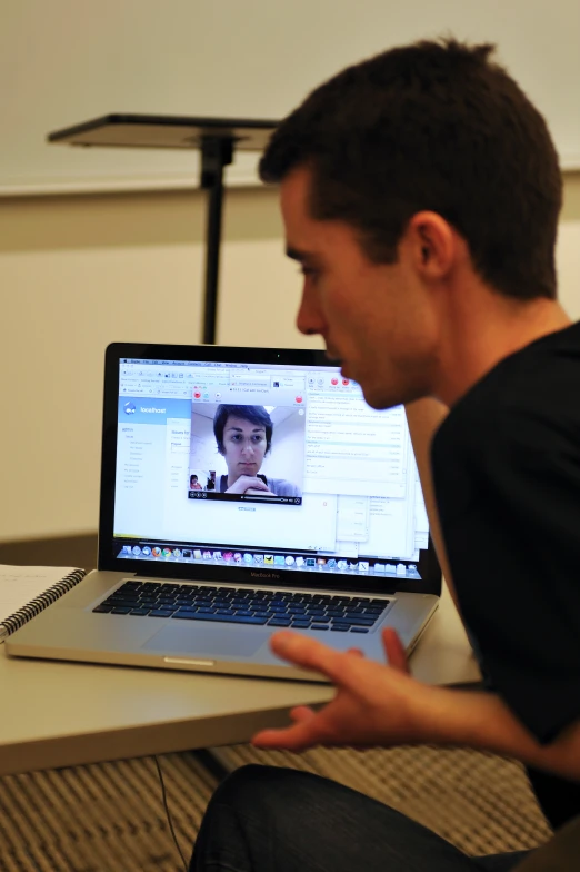 a young man is sitting down looking at a laptop computer