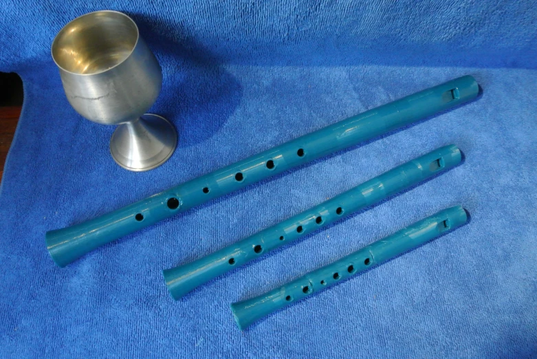 blue instruments are on a blue blanket next to a metal cup