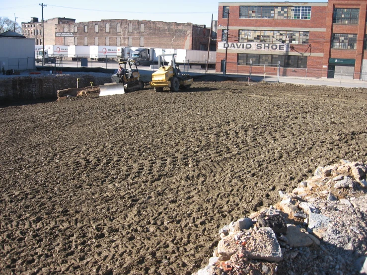 large dirty field with construction vehicles in the background