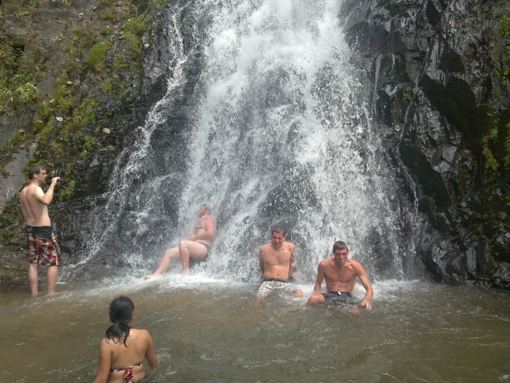 the people are enjoying the waterfall bath in the water