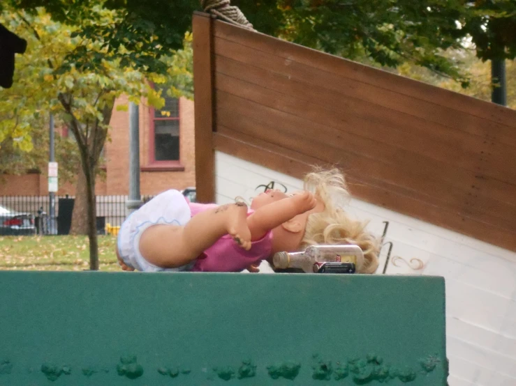 a little girl falling from a bench with a teddy bear