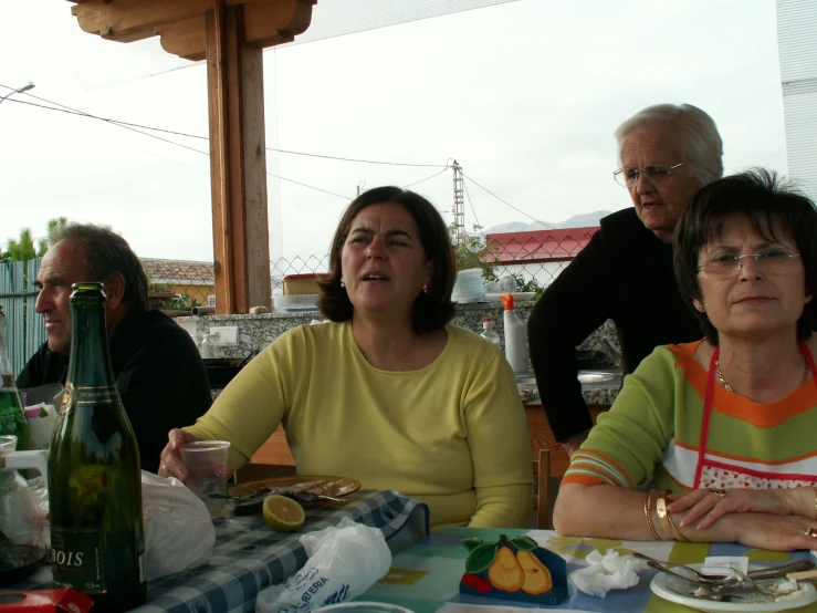 an elderly woman sitting next to two younger ladies and an old man eating