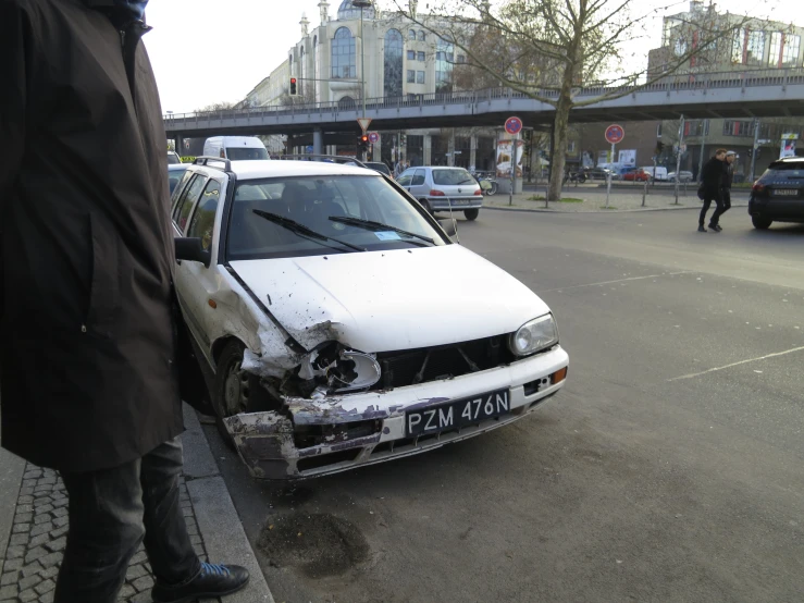 a damaged car is stopped on the street by a man