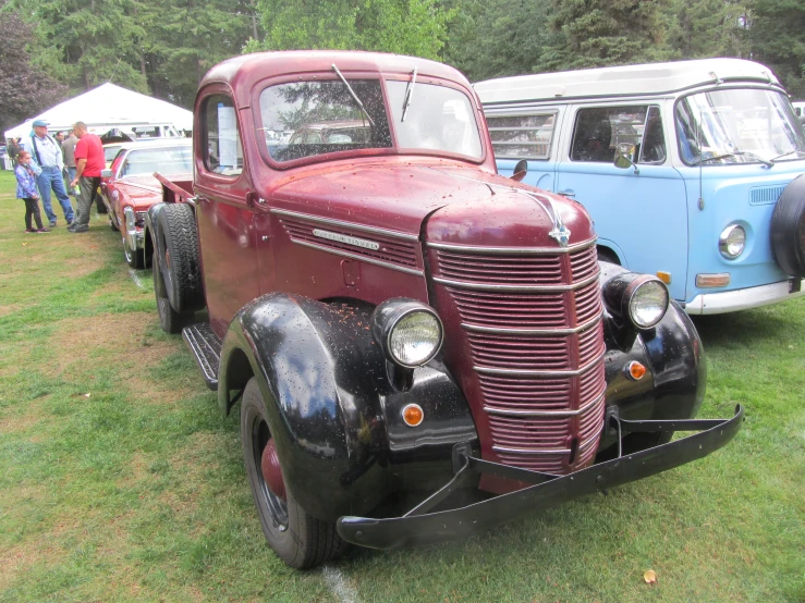 a very old timey truck sitting on top of a grass covered field