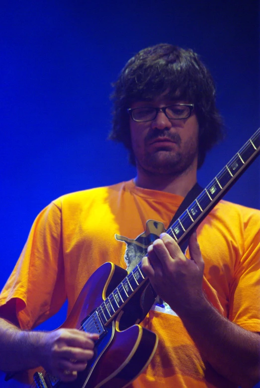 a man in a yellow shirt playing a guitar