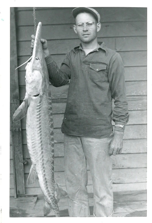 a man holding a fish in his hand while wearing a hat